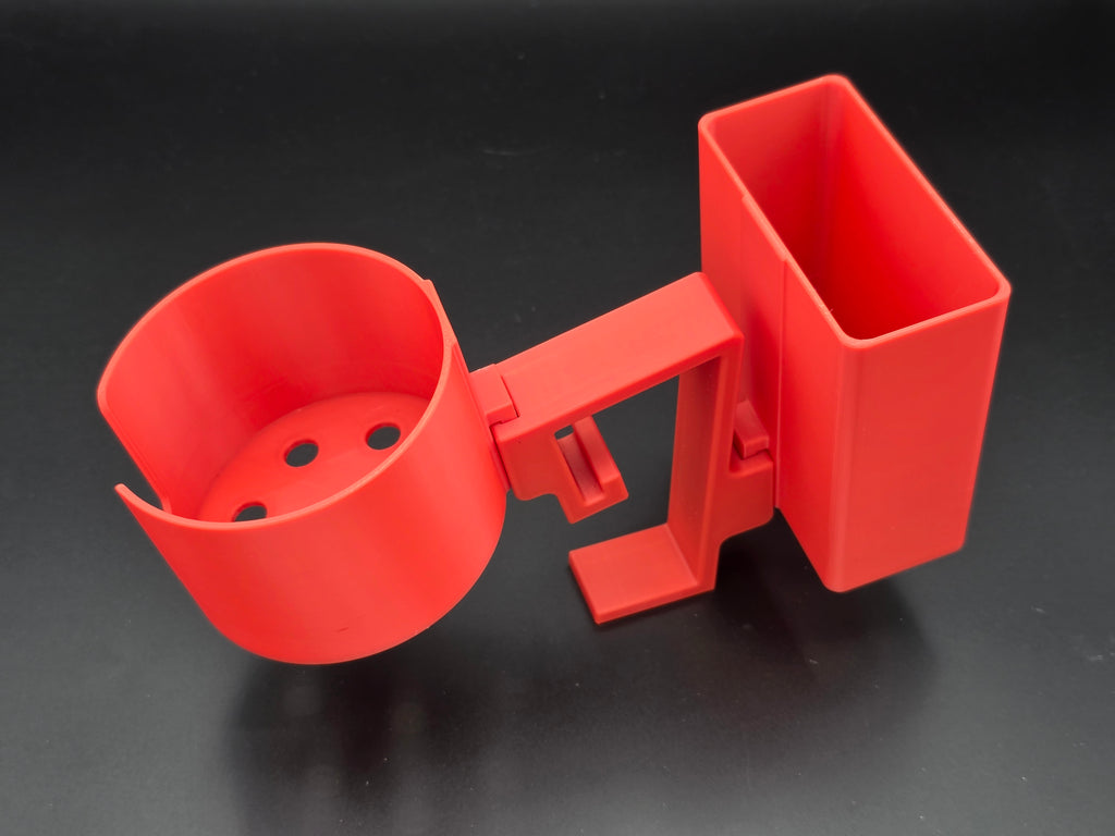 A studio-style shot of a single red, 3D-printed cup and cell phone holder attachment for a Tarter poly stock tank, isolated against a smooth black background. The cup holder features a deep cylindrical cup with five drainage holes at the bottom and a large side notch for mug handles. The cell phone holder is rectangular with rounded corners. Both holders are connected to a sturdy, integrated L-shaped mounting clip designed to hook over a thick tank rim, showcasing the smooth finish.