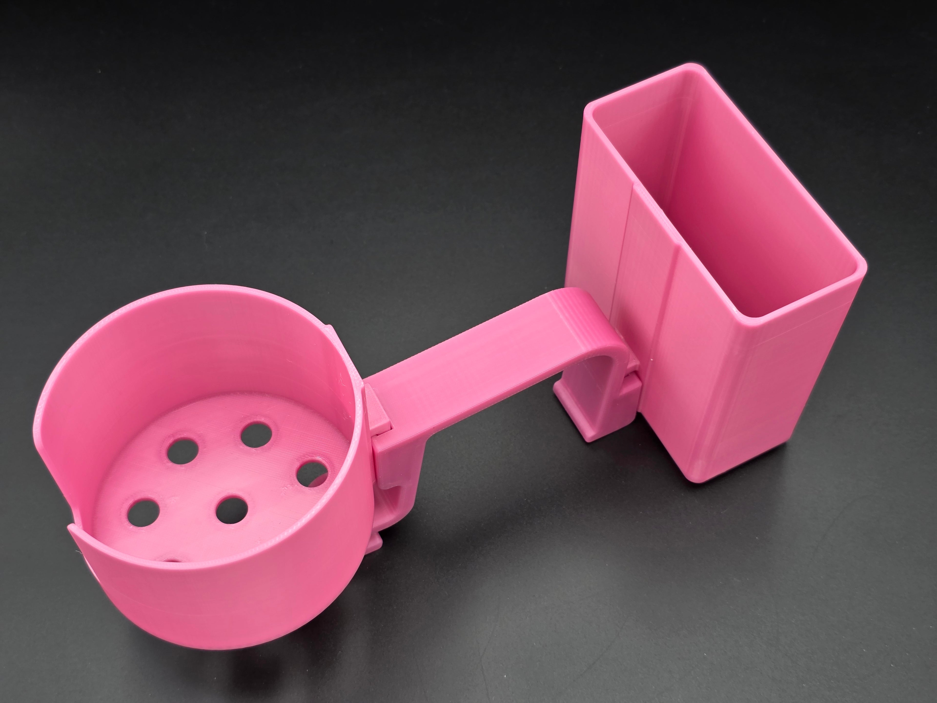 A studio-style shot of a single pink, 3D-printed cup and cell phone holder attachment for a Hastings poly stock tank, isolated against a smooth black background. The cup holder features a deep cylindrical cup with five drainage holes at the bottom and a large side notch for mug handles. The cell phone holder is rectangular with rounded corners. Both holders are connected to a sturdy, integrated L-shaped mounting clip designed to hook over a thick tank rim, showcasing the smooth finish.