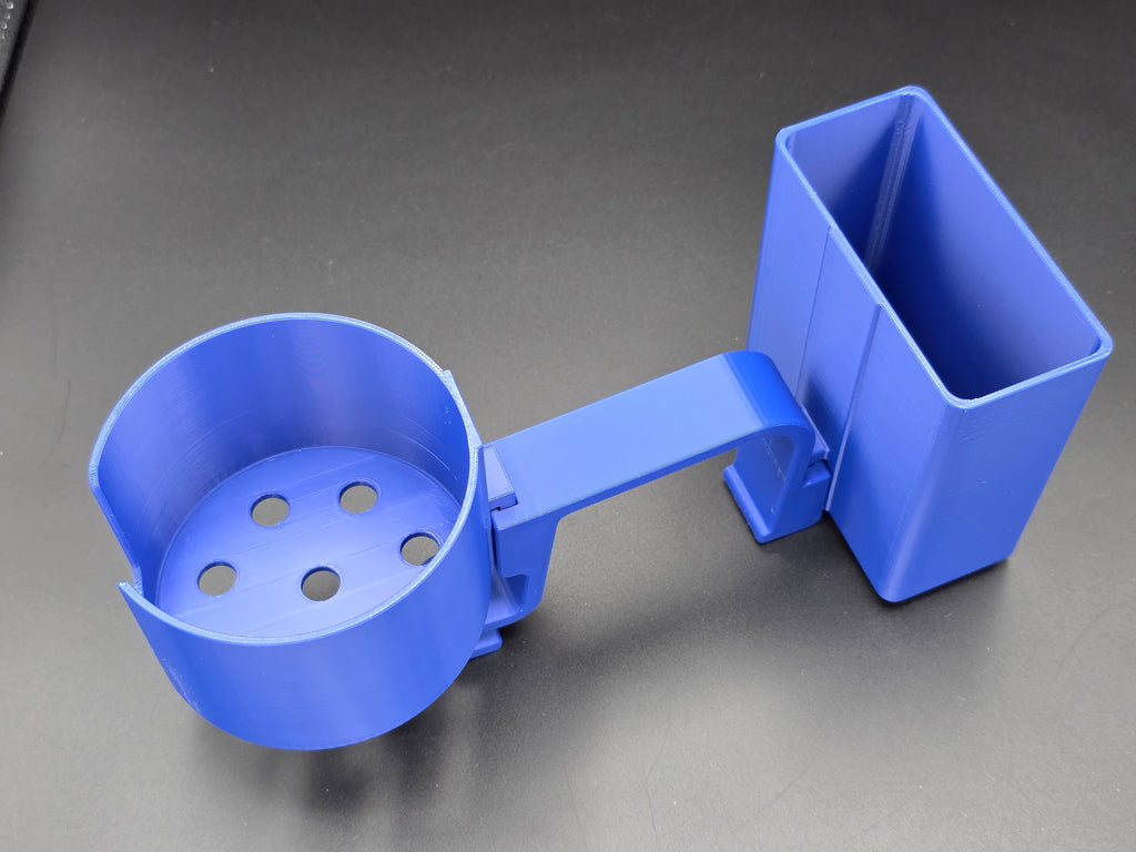 A studio-style shot of a single blue, 3D-printed cup and cell phone holder attachment for a Hastings poly stock tank, isolated against a smooth black background. The cup holder features a deep cylindrical cup with five drainage holes at the bottom and a large side notch for mug handles. The cell phone holder is rectangular with rounded corners. Both holders are connected to a sturdy, integrated L-shaped mounting clip designed to hook over a thick tank rim, showcasing the smooth finish.