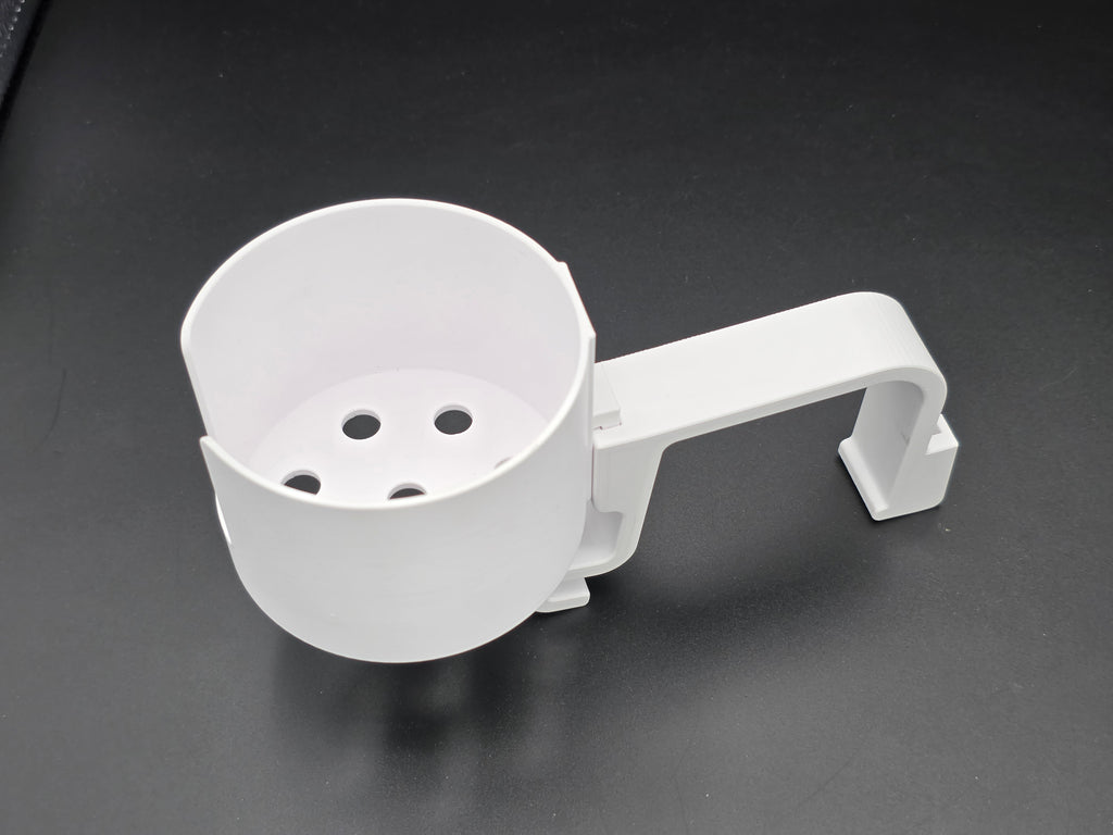 A studio-style shot of a single white, 3D-printed cup holder attachment for a Hastings poly stock tank, isolated against a smooth black background. The holder features a deep cylindrical cup with five drainage holes at the bottom and a large side notch for mug handles. It is connected to a sturdy, integrated L-shaped mounting clip designed to hook over a thick tank rim, showcasing the smooth finish and solid plastic construction of the UV-stable PETG material.