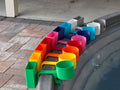 A row of colorful cup holders with cell phone caddies in various colors, including green, yellow, orange, red, pink, blue, light blue, white, and grey. Each holder is attached to the rim of a grey stock tank, creating a vibrant and organized display.