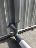 A square grey metal gutter is being adapted to 4" Sewer & Drain (S&D) PVC piping. The 3D Printed adapter and the PVC have been painted tom closely match the grey of the downspout. 