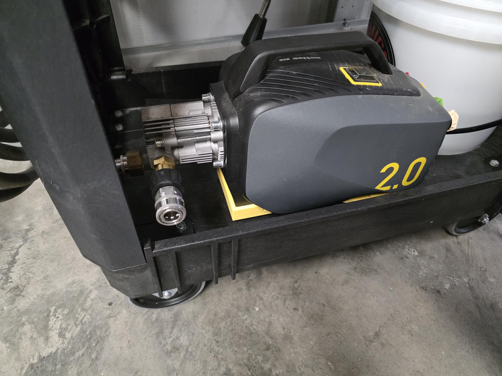 A 3D printed cradle for the Active 2.0 pressure washer power head shown in yellow with included stainless hardware. The image is a close-up of the cradle installed on an a black Kobalt branded utility cart with the Active 2.0 pressure washer placed into the cradle. 
