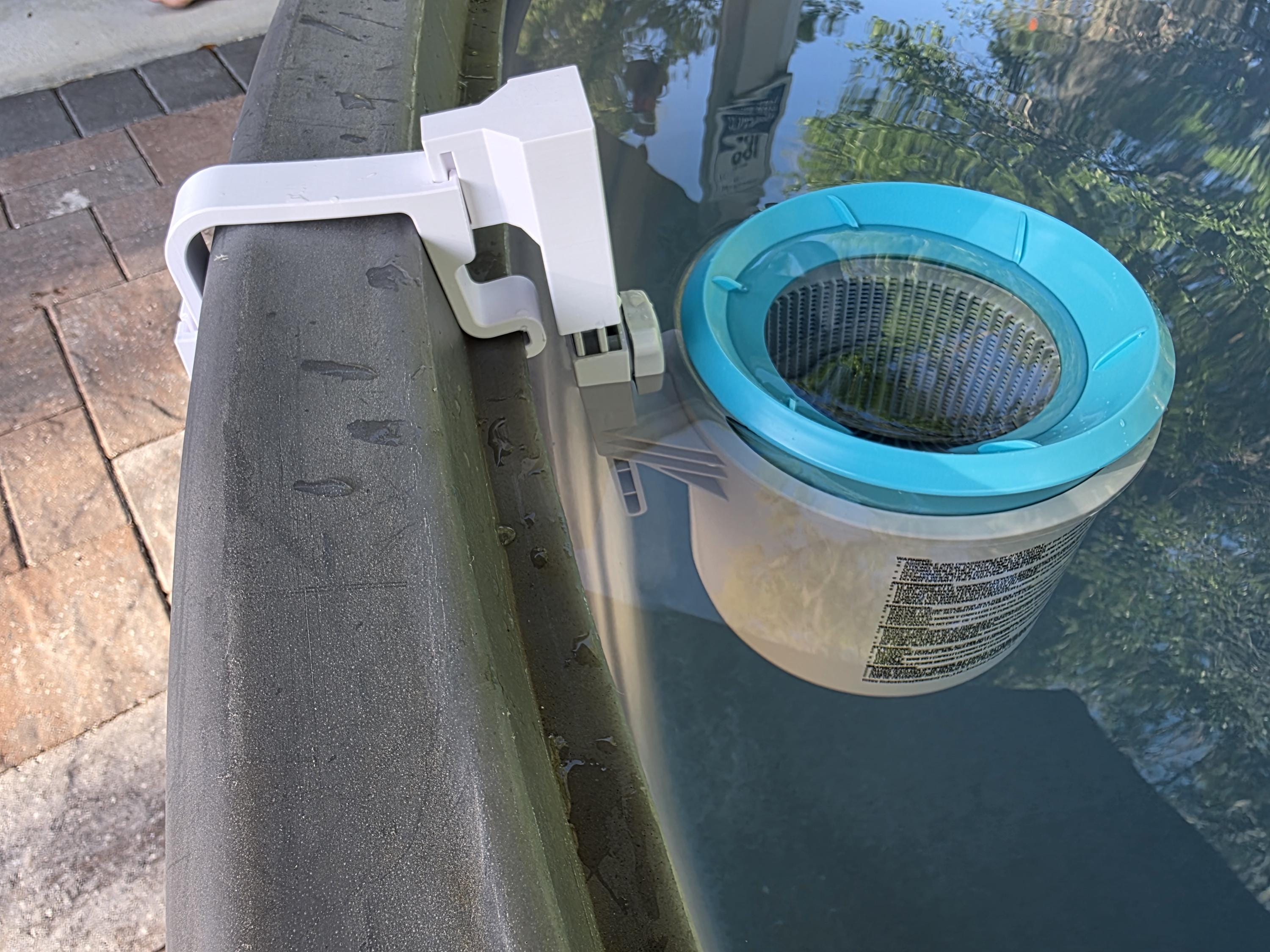 A close-up image of an Intex above ground pool skimmer installed onto a grey poly stock tank using a grey 3D printed bracket and a grey adapter to the Intex skimmer support rod. 