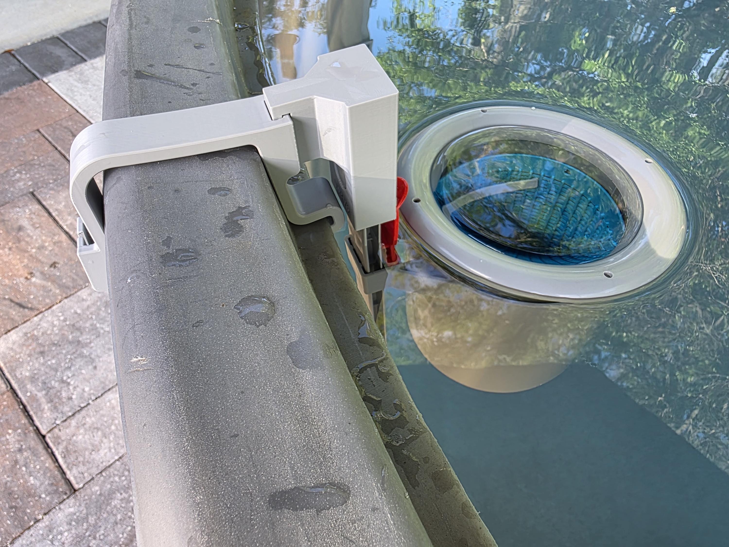 A close-up image of a US Pool Supply above ground pool skimmer installed onto a grey poly stock tank using a grey 3D printed bracket and a grey adapter to the US Pool Supply skimmer support rod. 