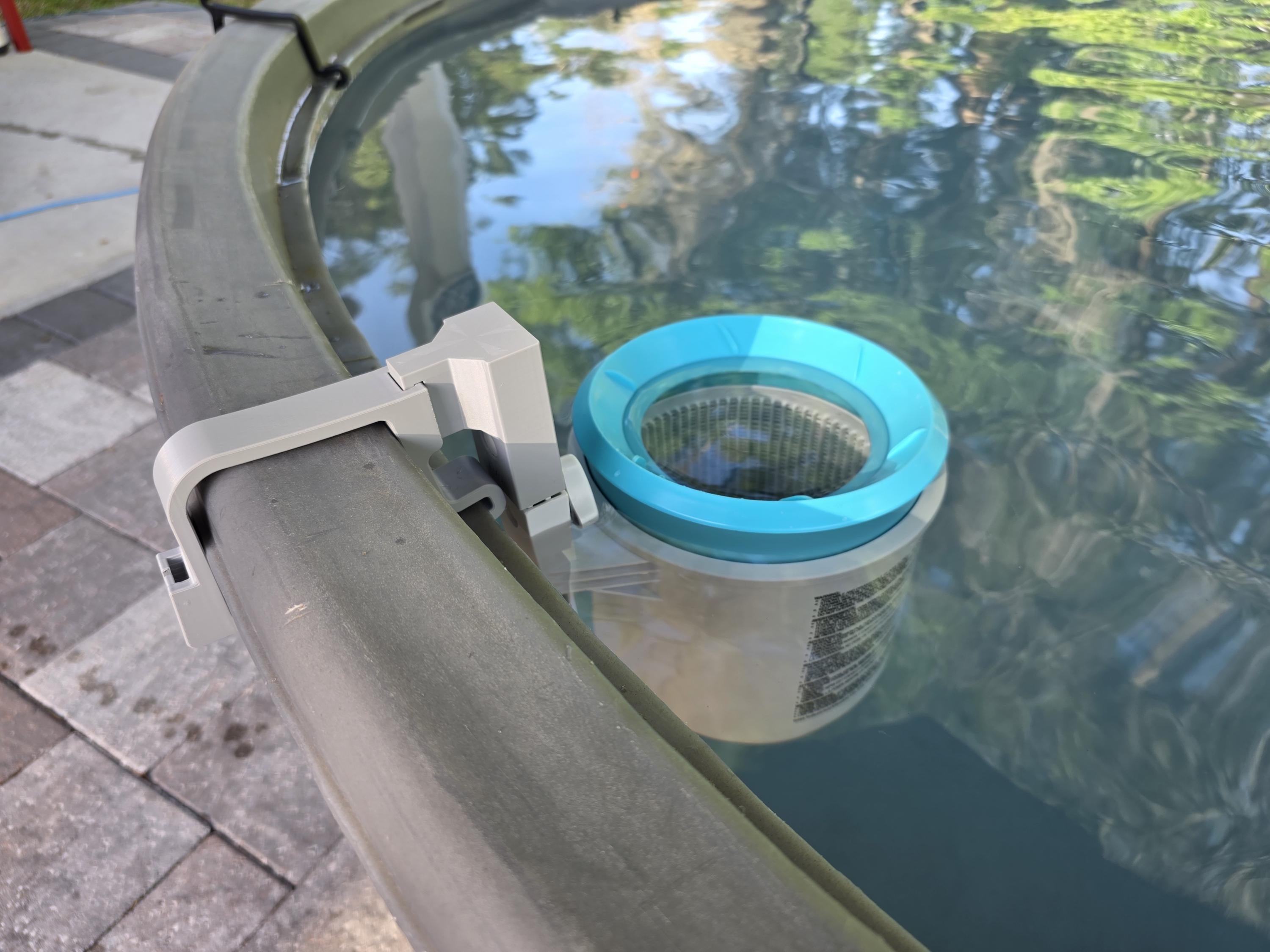 A close-up image of an Intex above ground pool skimmer installed onto a grey poly stock tank using a grey 3D printed bracket and a grey adapter to the Intex skimmer support rod. 