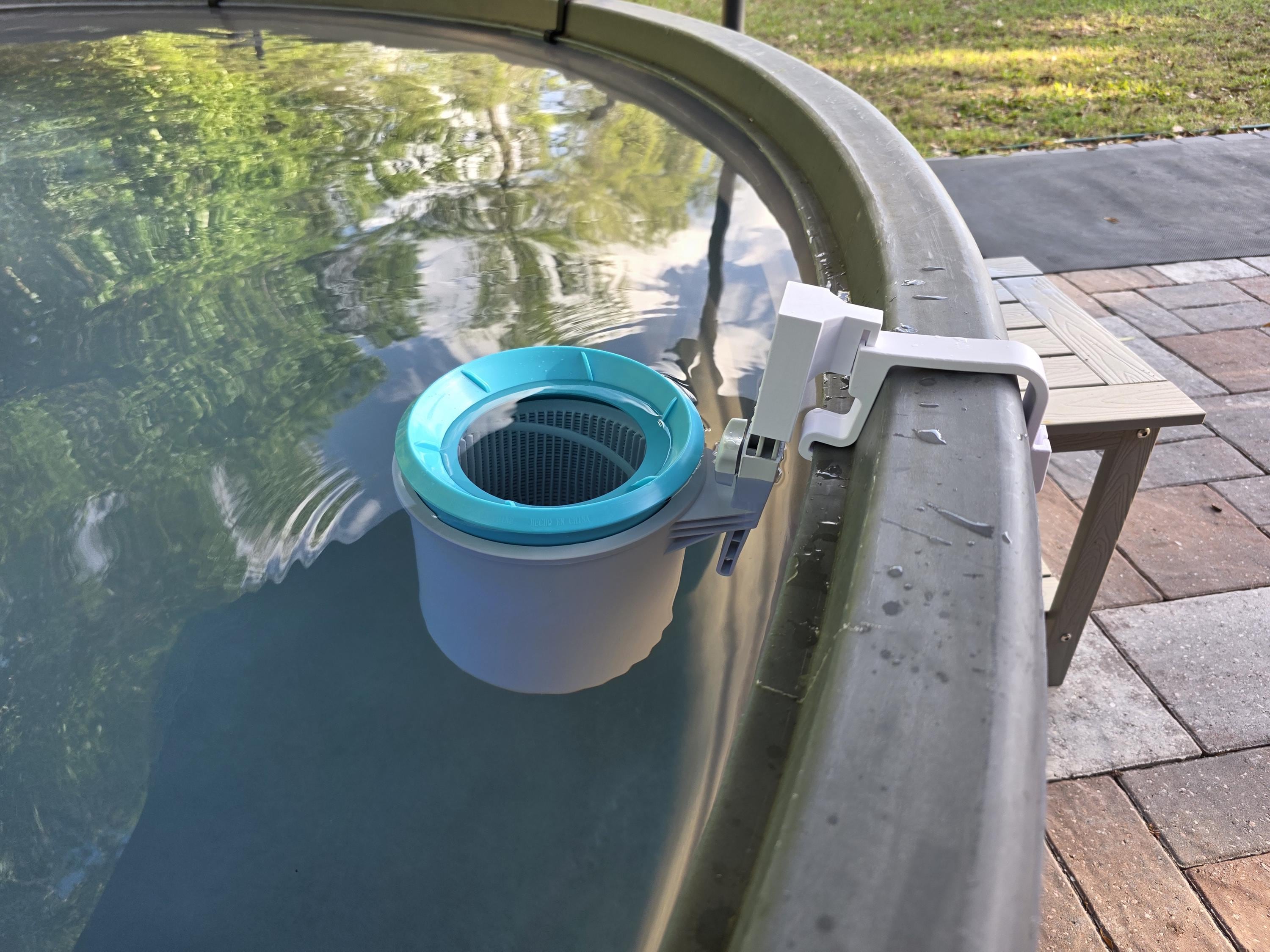 An Intex above ground pool skimmer installed onto a grey poly stock tank using a white 3D printed bracket and a white adapter to the Intex skimmer support rod. 